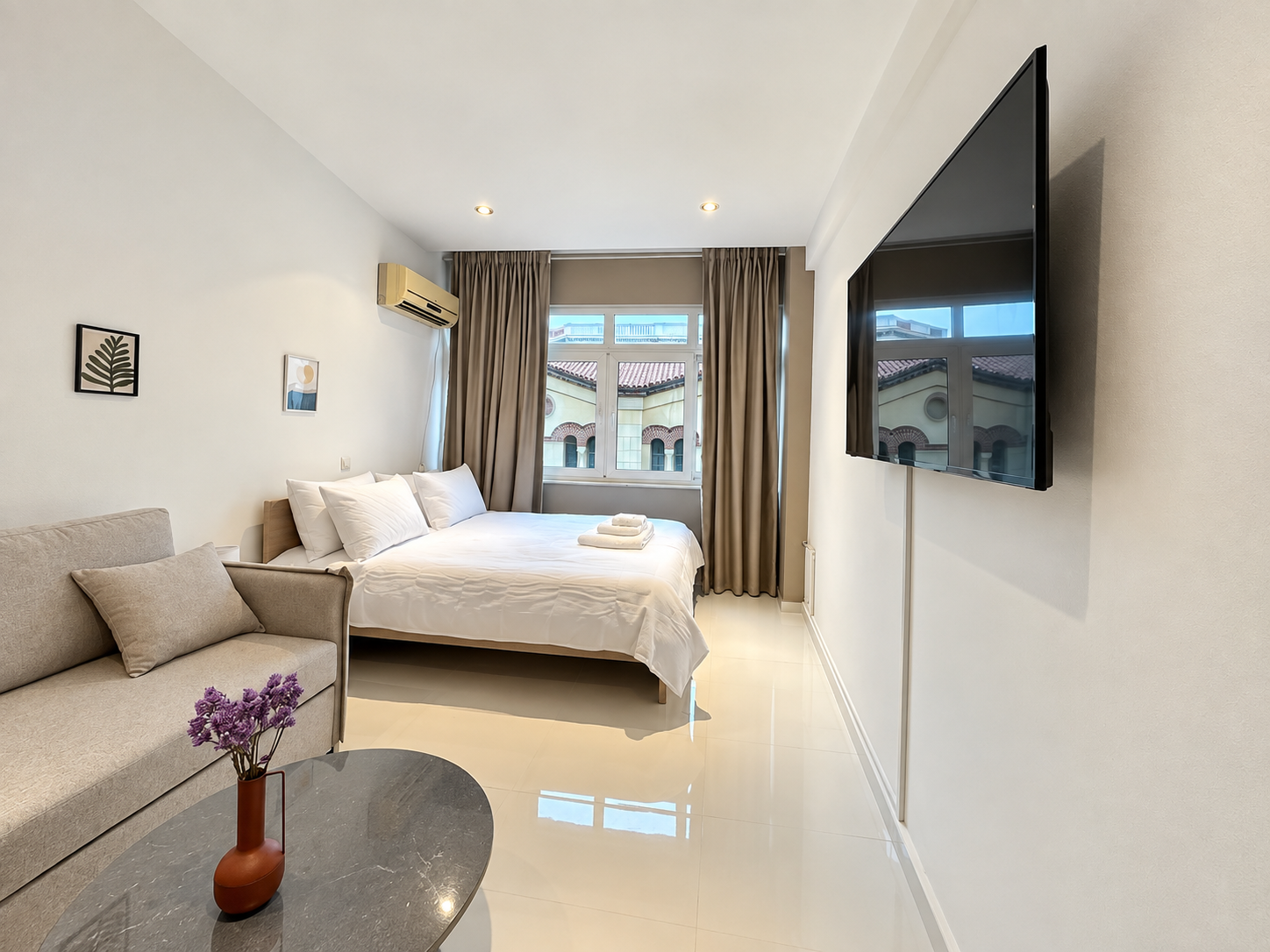Bright furnished studio with double bed, sofa and wall-mounted TV at Karytsi Square 3, Athens